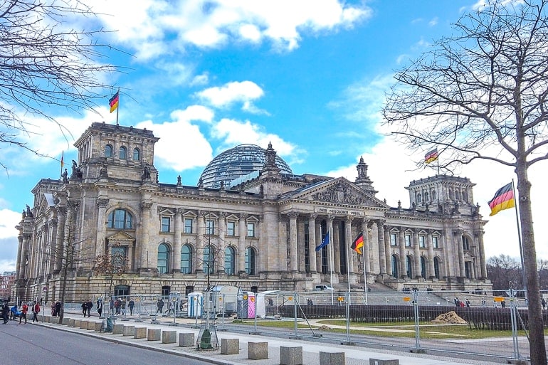 domed building with german flags flying in berlin on germany itinerary