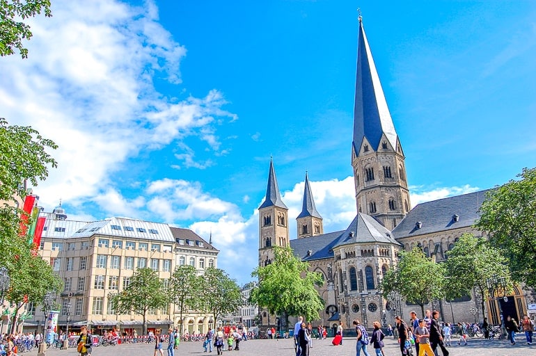 tall church spire and open public square with blue sky above in bonn germany